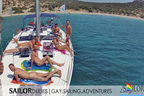 Naked group of gay guys sunbathing on sailing yacht