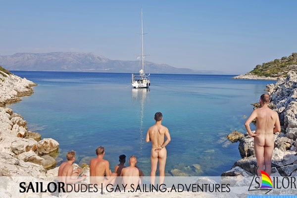 Nude gay guys on beach in Greece watching a sailing yacht