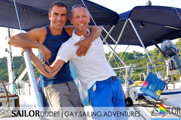 Two gay skippers on stern of sailing yacht